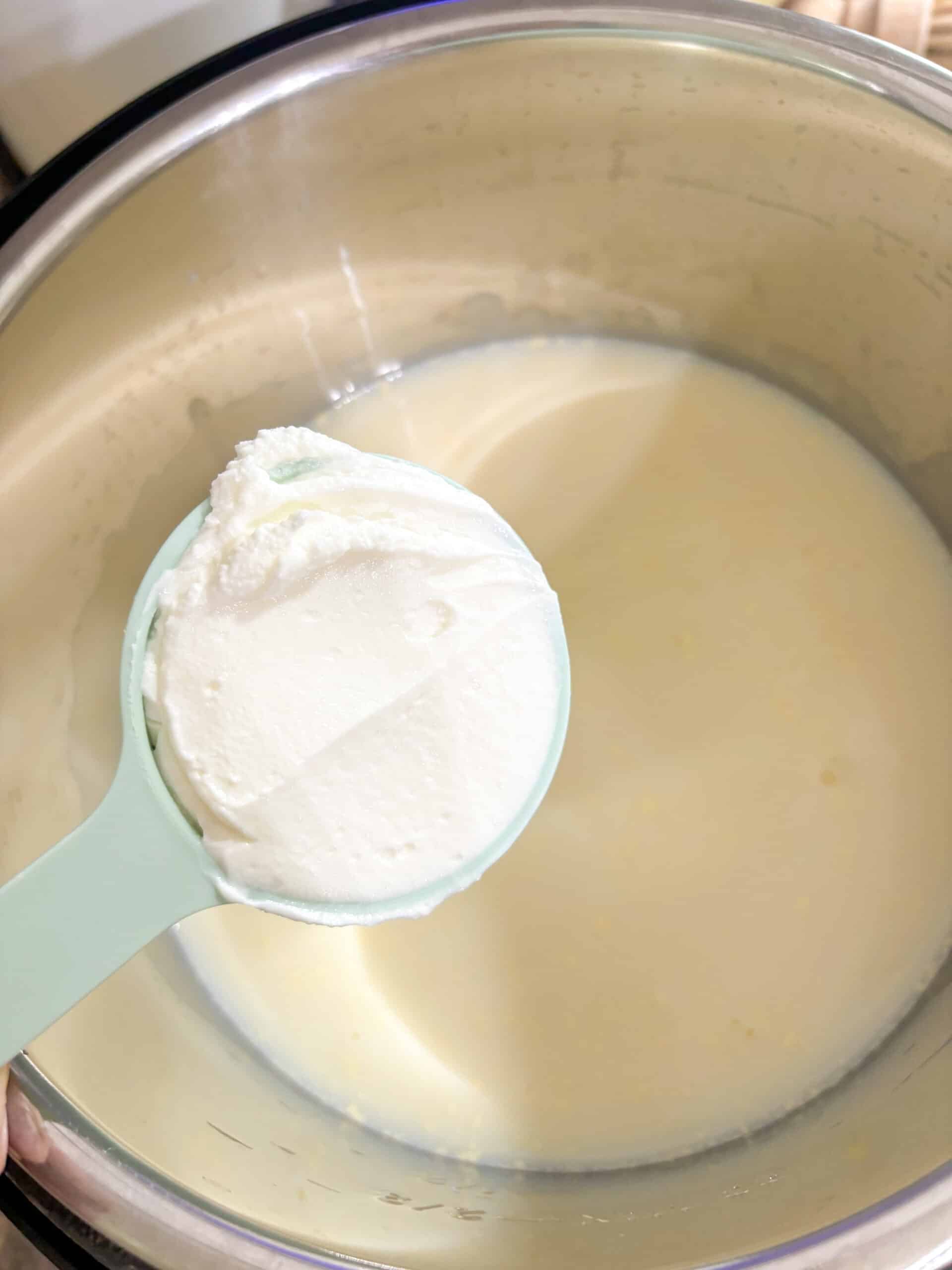 Step one of the super easy homemade Greek yogurt recipe, adding the yogurt starter culture to the raw milk