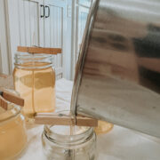 Pouring the homemade beeswax candles into the jars