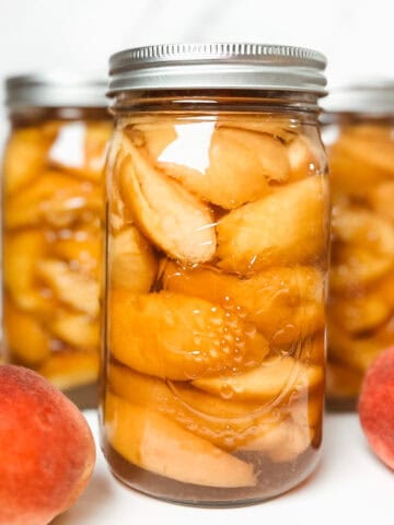 featured image of pretty canned peaches in jars with some fresh peaches